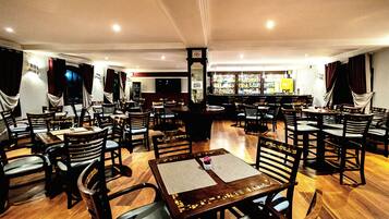 A restaurant with multiple tables and chairs, a bar area, and a clock on the wall.