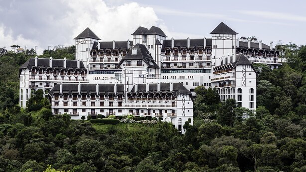 A large, multi-story building with a symmetrical facade, multiple balconies, and a central tower. - Home Green Home (Campos do Jordão)