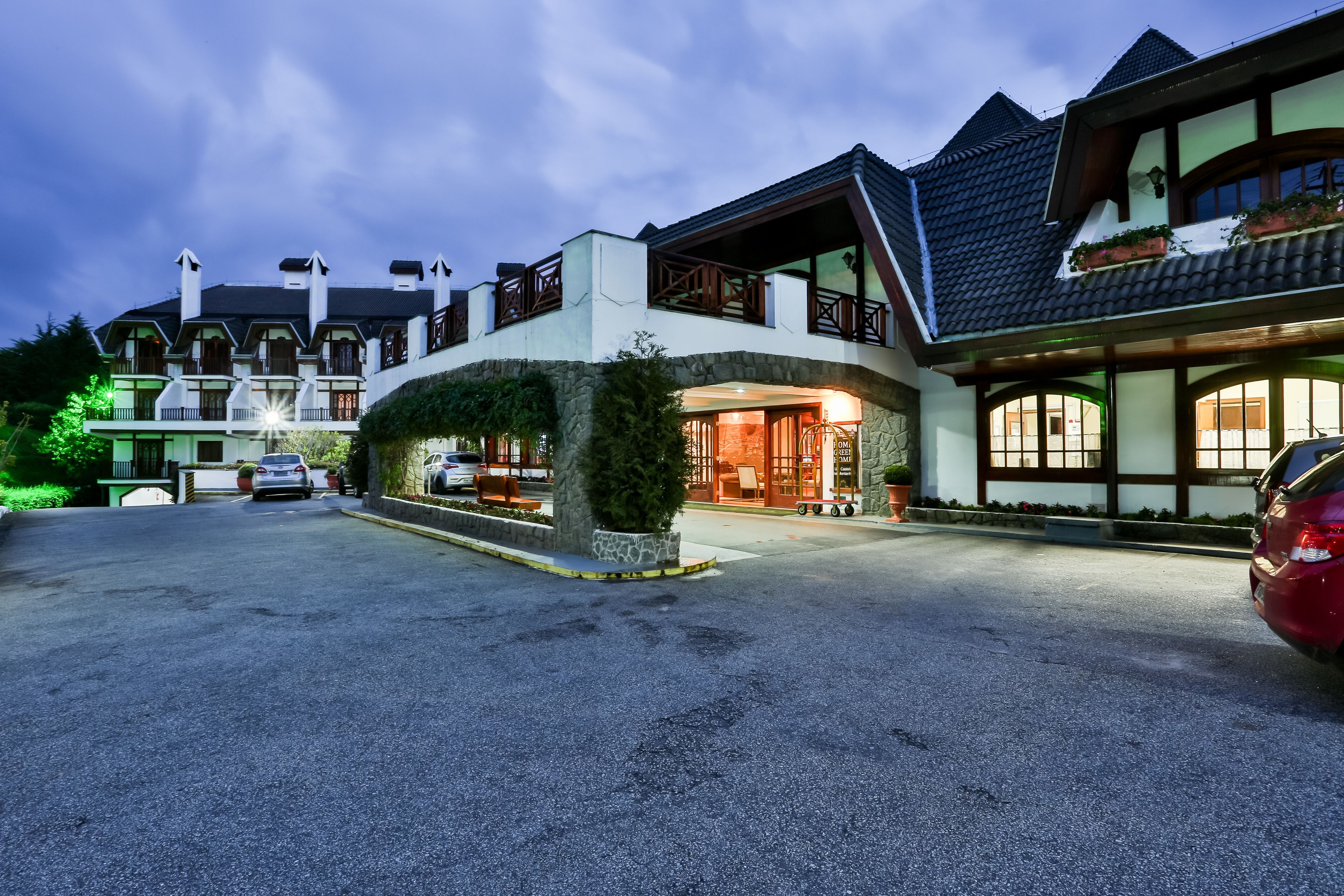 A modern hotel with a spacious driveway, a covered entrance, and a well-maintained garden area.