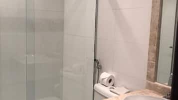 A modern bathroom with a glass-enclosed shower, a white toilet, and a marble sink.
