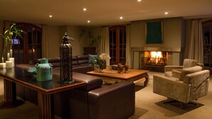 A living room with a fireplace, leather sofas, a coffee table, and decorative items. - Home Green Home (Campos do Jordão)
