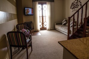 A living room with a sofa, a striped chair, a television, and a staircase. - Home Green Home (Campos do Jordão)