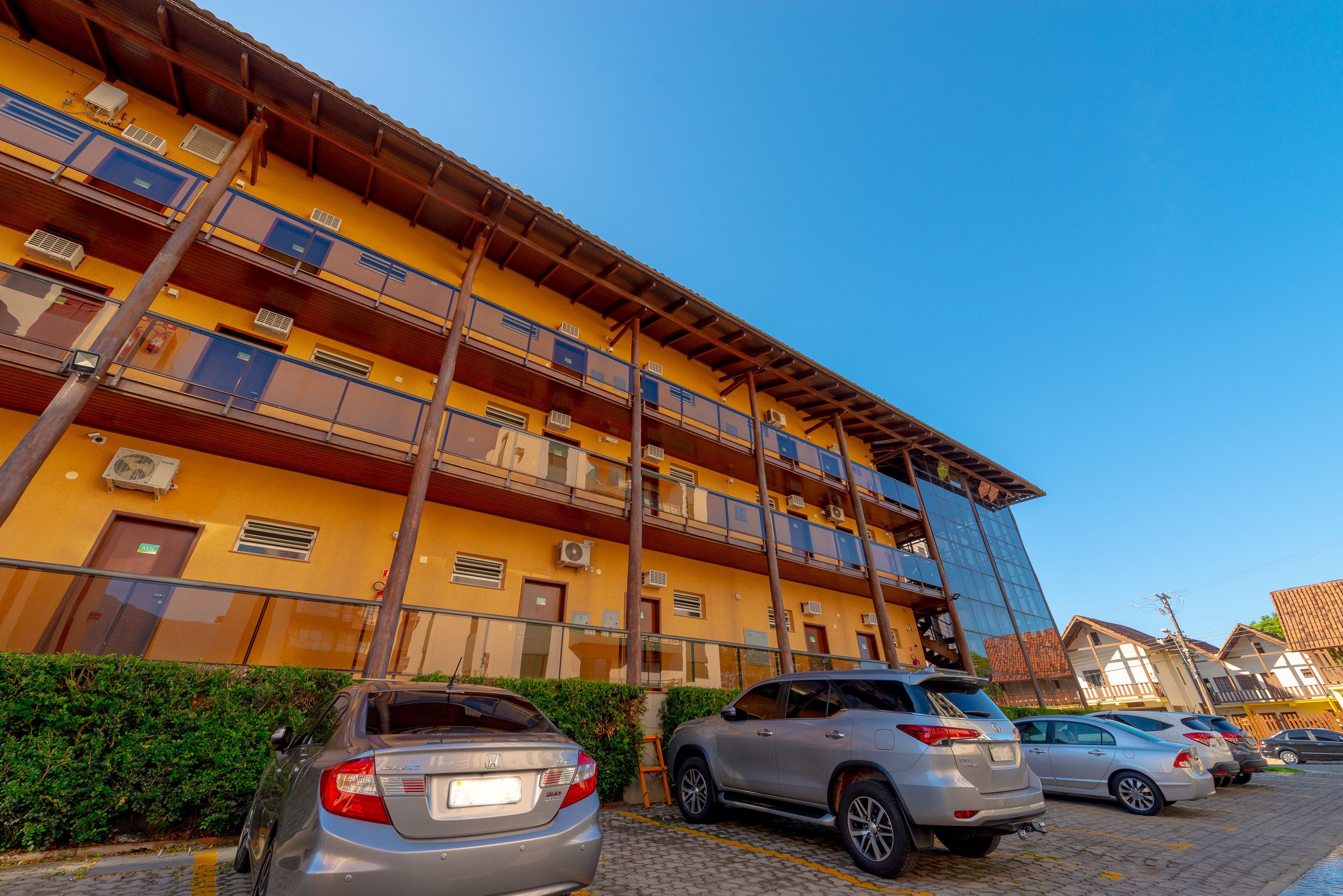 A multi-story building with balconies and parked cars.