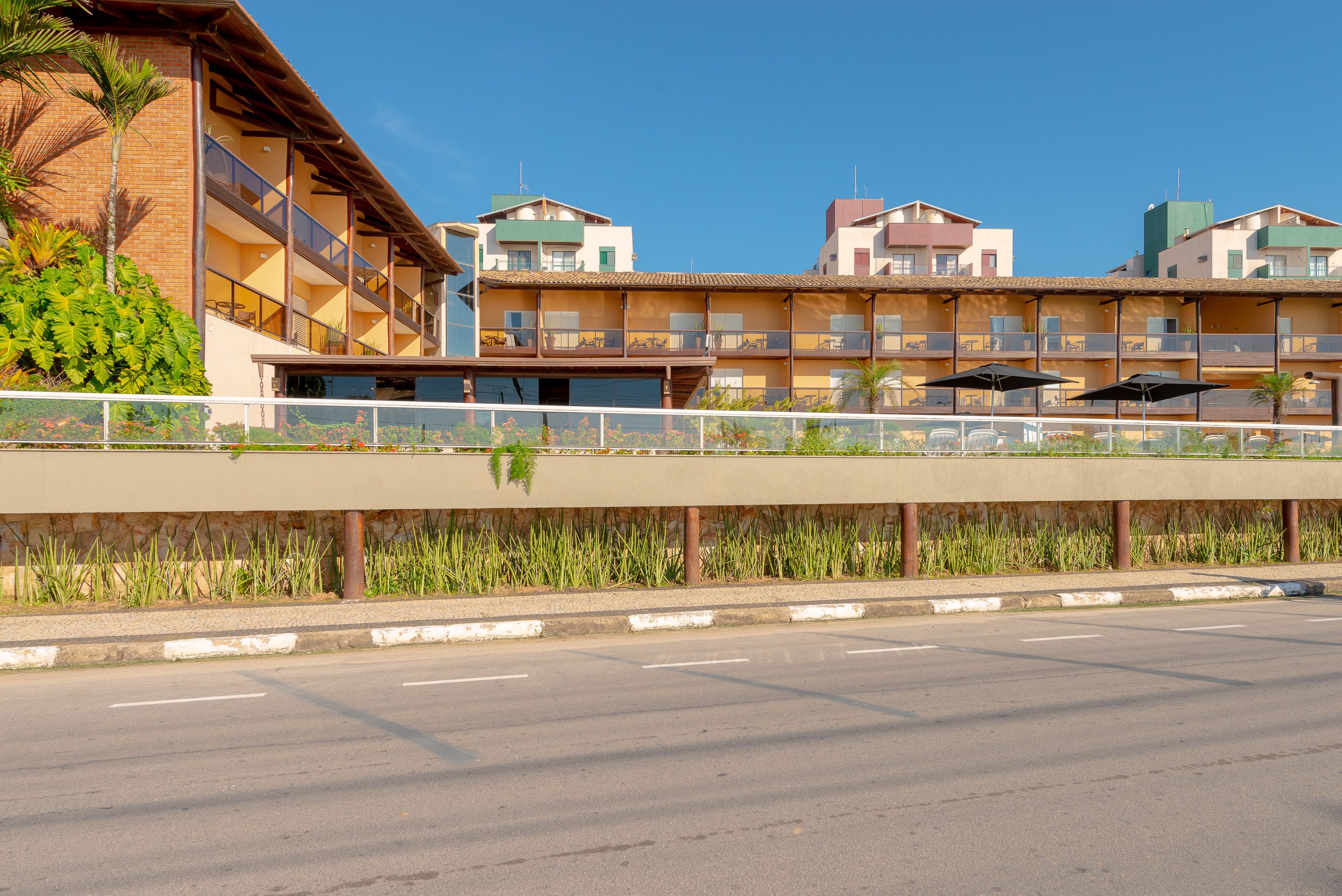 A multi-story hotel with balconies, outdoor seating, and a pedestrian bridge.