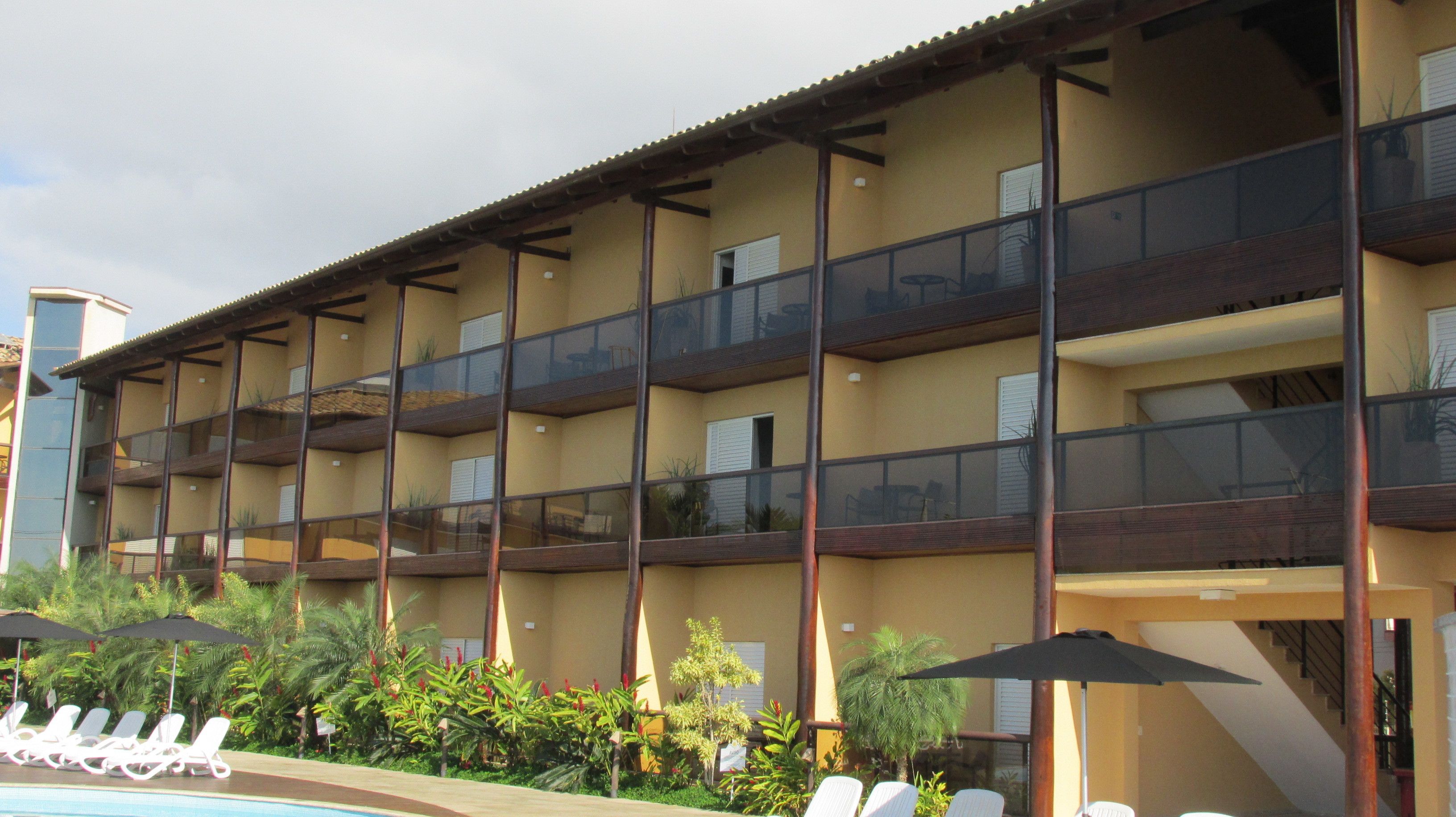 Un hôtel à plusieurs étages doté de balcons, d’une piscine et de chaises longues.