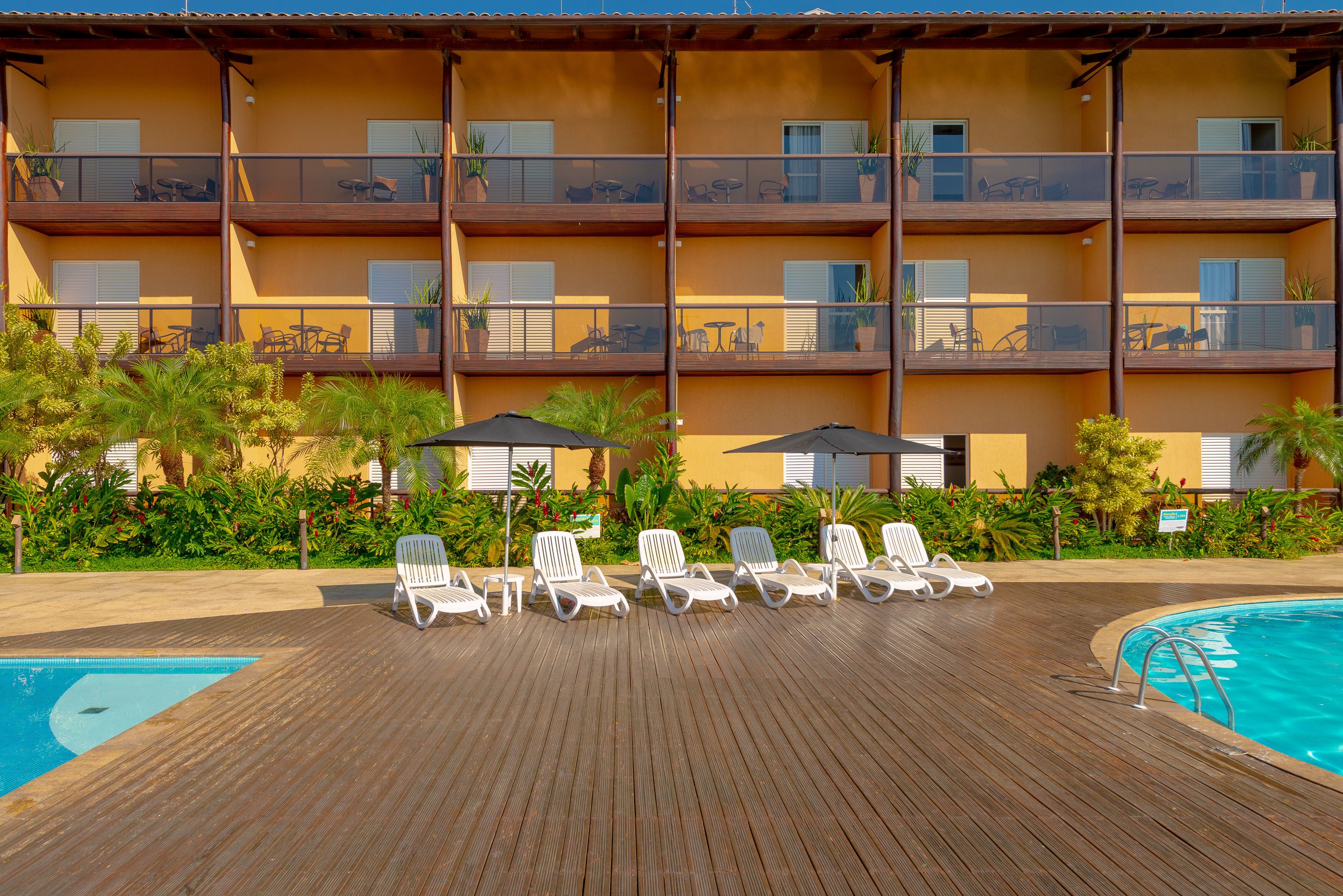 Ein Hotel mit Poolbereich, mehreren Balkonen und Sitzgelegenheiten im Freien.
