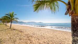 Una playa arenosa con palmeras y un cielo azul despejado.