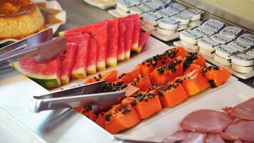 A buffet with sliced watermelon and papaya, and various packaged goods.