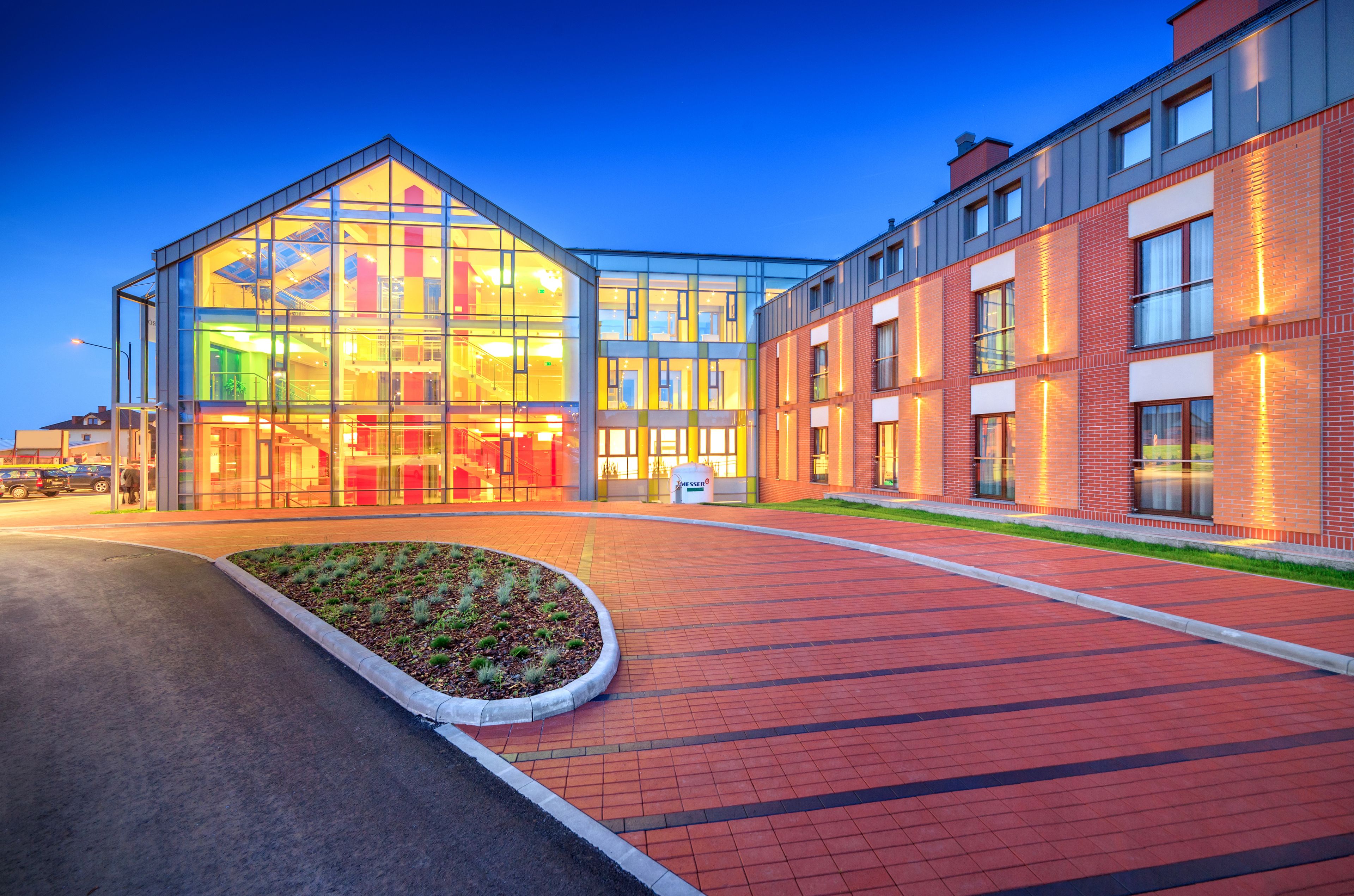 Een modern gebouw met grote glasramen en een gevel van baksteen.