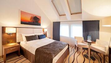 Habitación de hotel con una cama grande, un escritorio, una silla, una ventana con cortinas y un cuadro en la pared.