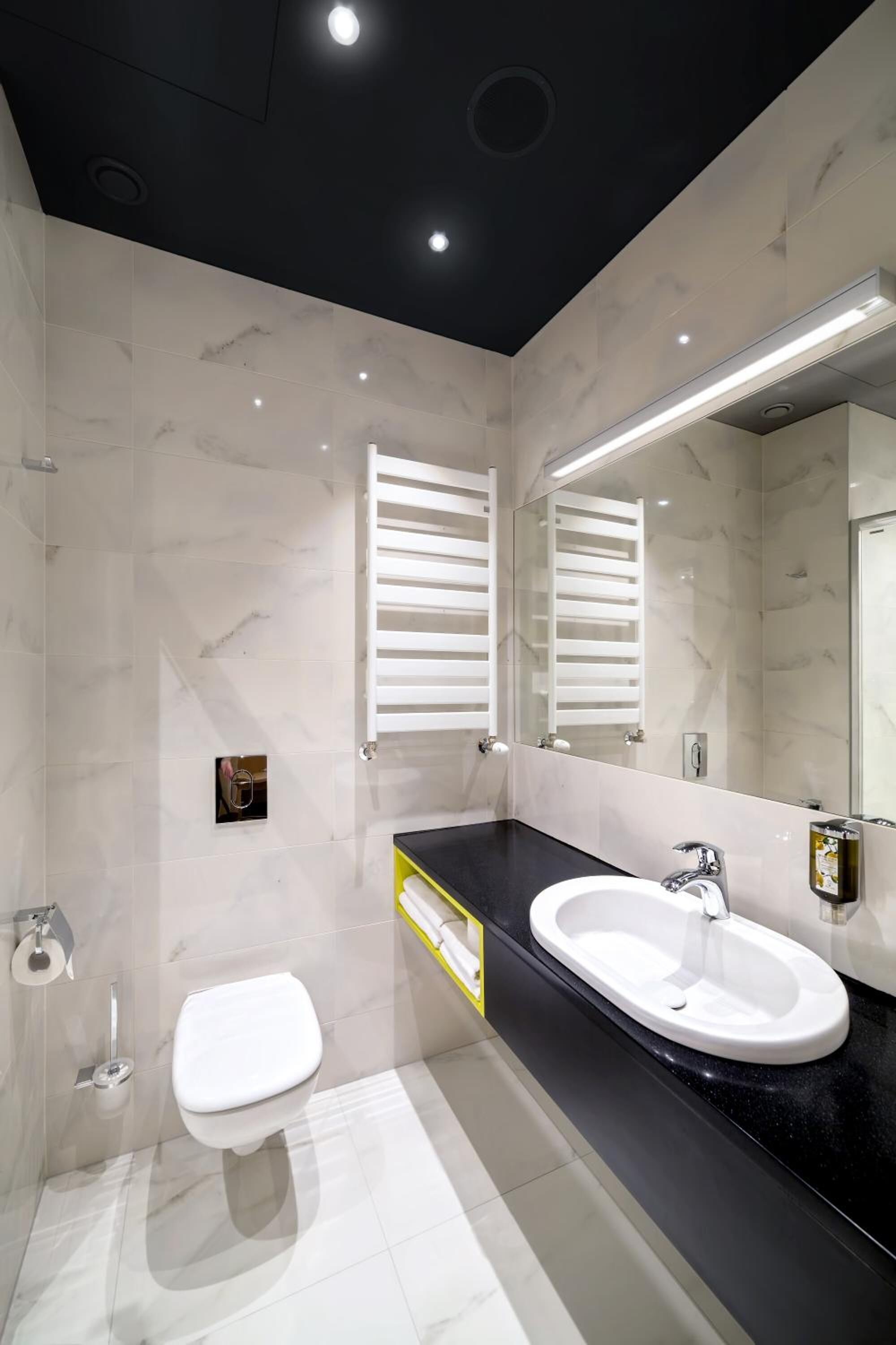 A modern bathroom with a black countertop, white sink, and a large mirror.