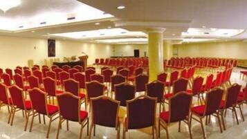 A conference room with rows of red chairs arranged in a semi-circle, a podium, and a large pillar.