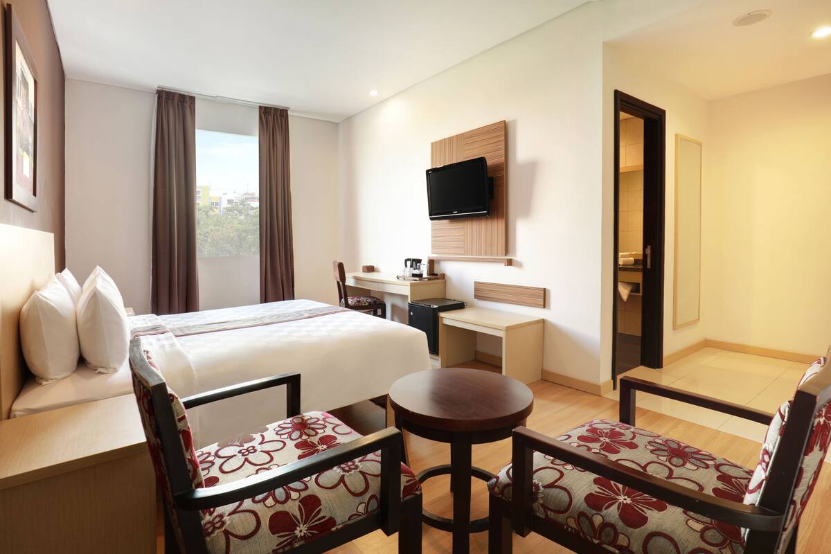Una habitación de hotel con cama, escritorio, televisión y dos sillas.
