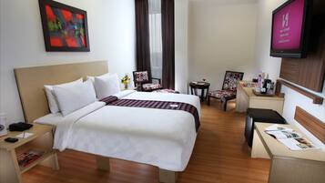 Habitación de hotel con dos camas, un escritorio, una silla, un televisor y un cuadro en la pared.
