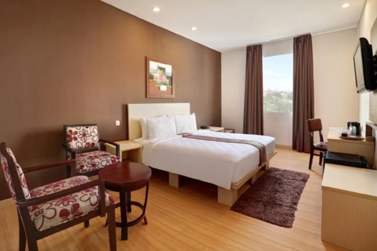 Una habitación de hotel con cama, escritorio, silla y una mesita.