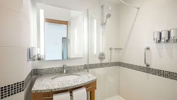 Une salle de bain moderne avec un lavabo en granit, une cabine de douche en verre et un miroir au-dessus du lavabo.