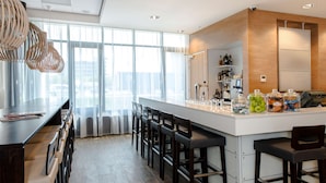 Cocina moderna con una isla central, taburetes de bar y vistas a la ciudad a través de amplios ventanales.