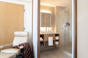A modern bathroom with a shower, a sink, and a chair. - Hotel Vermont (Burlington)