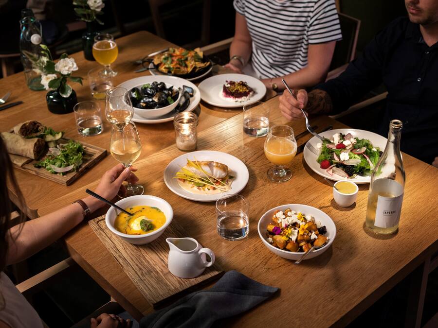 A wooden dining table with various dishes, glasses, and a bottle of wine.