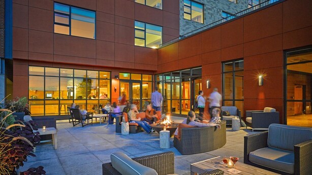 Un edificio moderno con un patio que incluye asientos al aire libre y una chimenea.