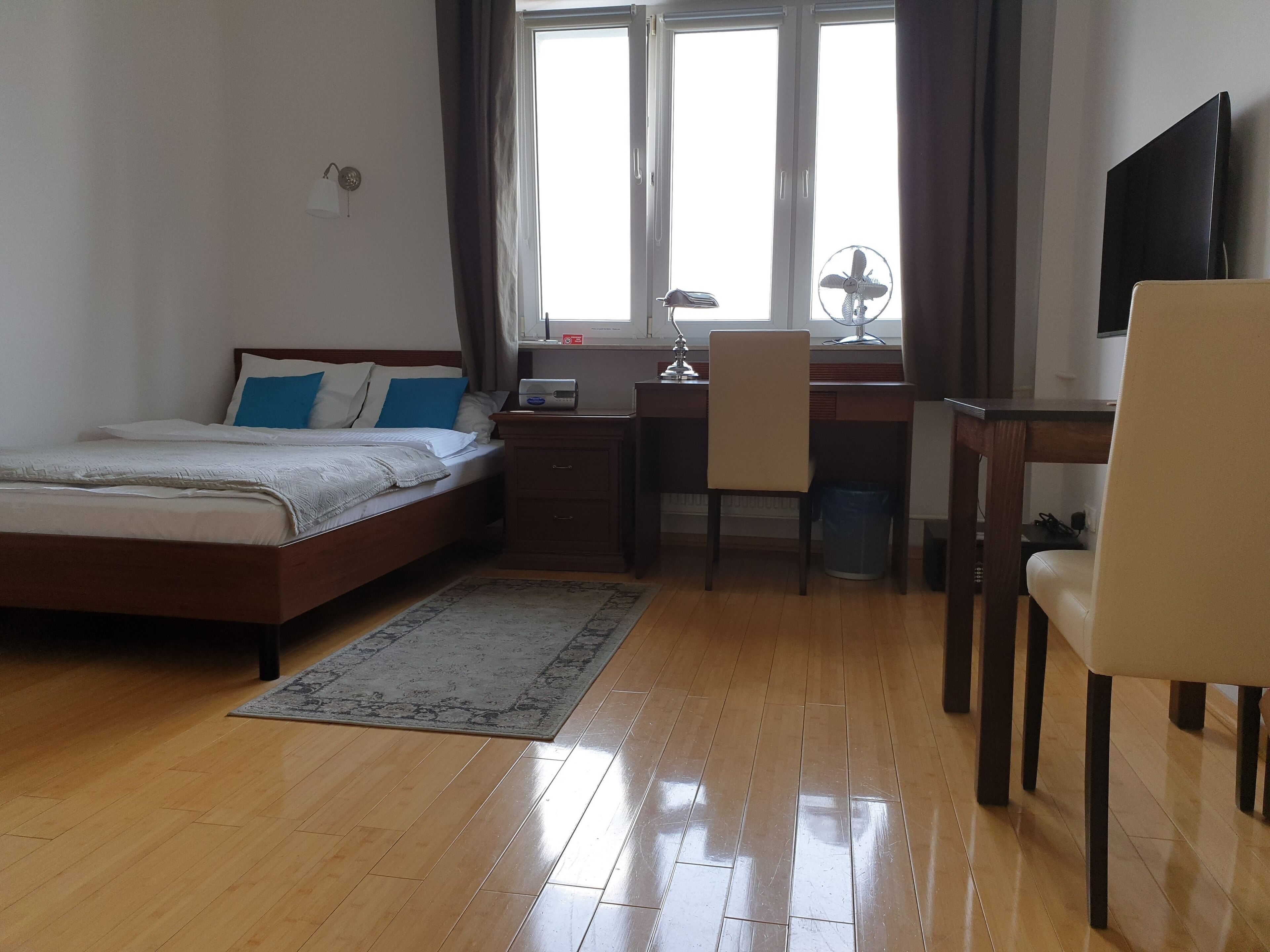 A bedroom with a bed, desk, chair, and a TV.