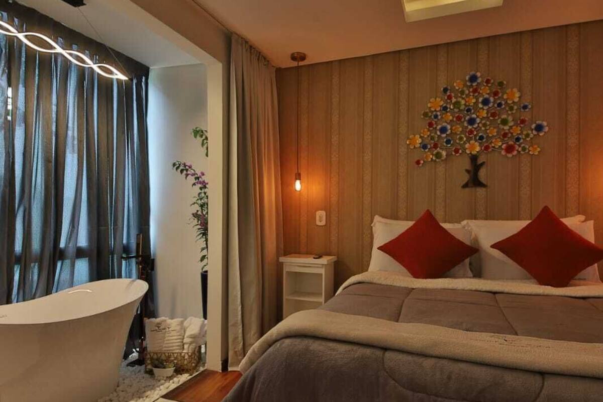 Een moderne slaapkamer met een groot bed, een badkuip en een bloemkunstwerk aan de muur.