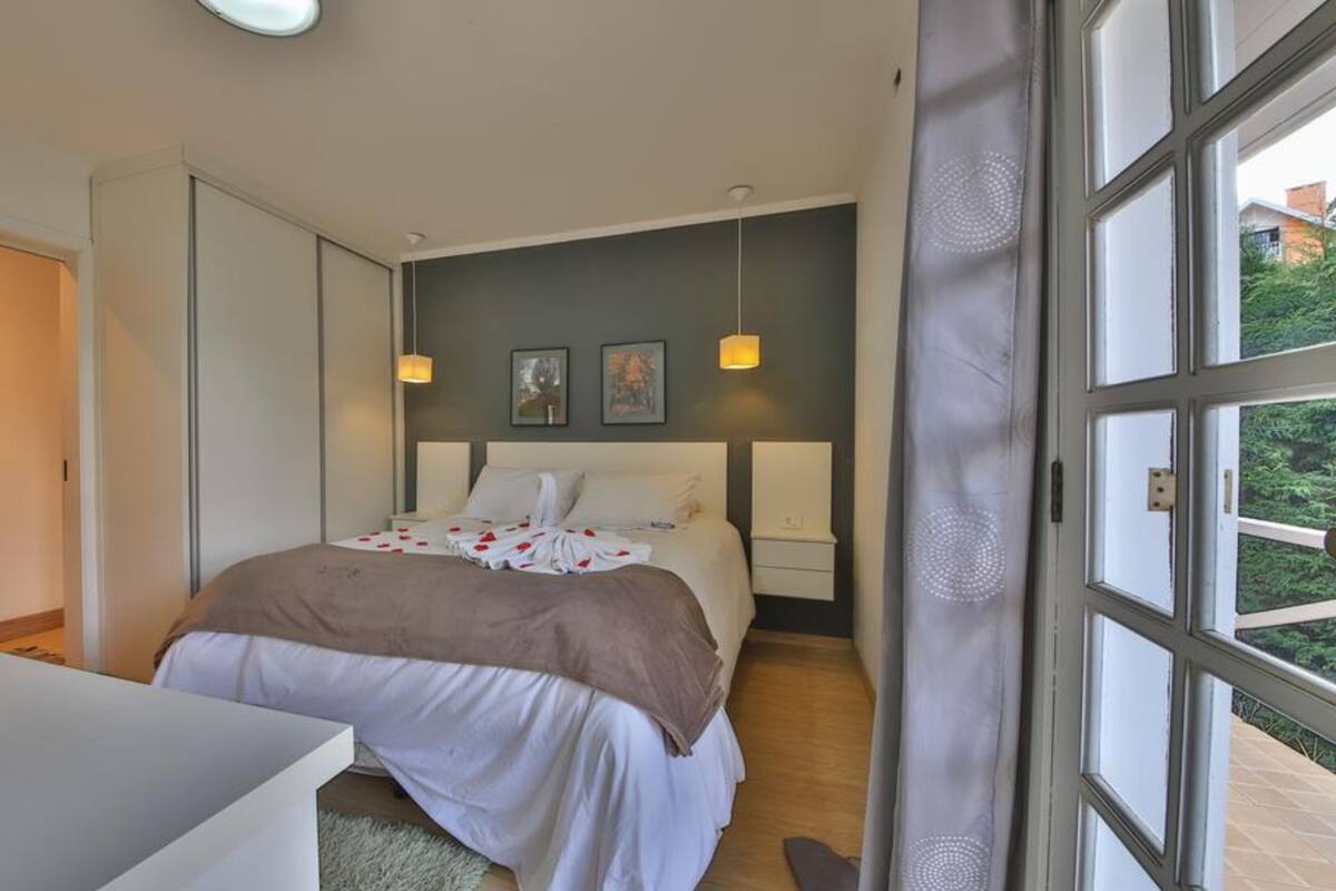 Een slaapkamer met een bed, nachtkastjes en uitzicht door een raam.