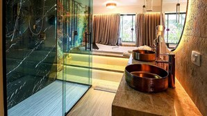 Une salle de bain moderne avec une paroi de séparation en verre, un meuble-lavabo en bois, des vasques en cuivre et un grand miroir.