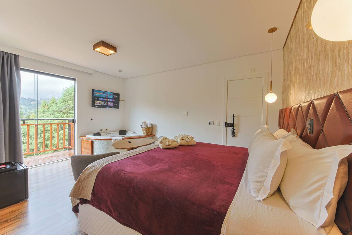 Een moderne slaapkamer met een groot bed, een bureau en uitzicht op een balkon.