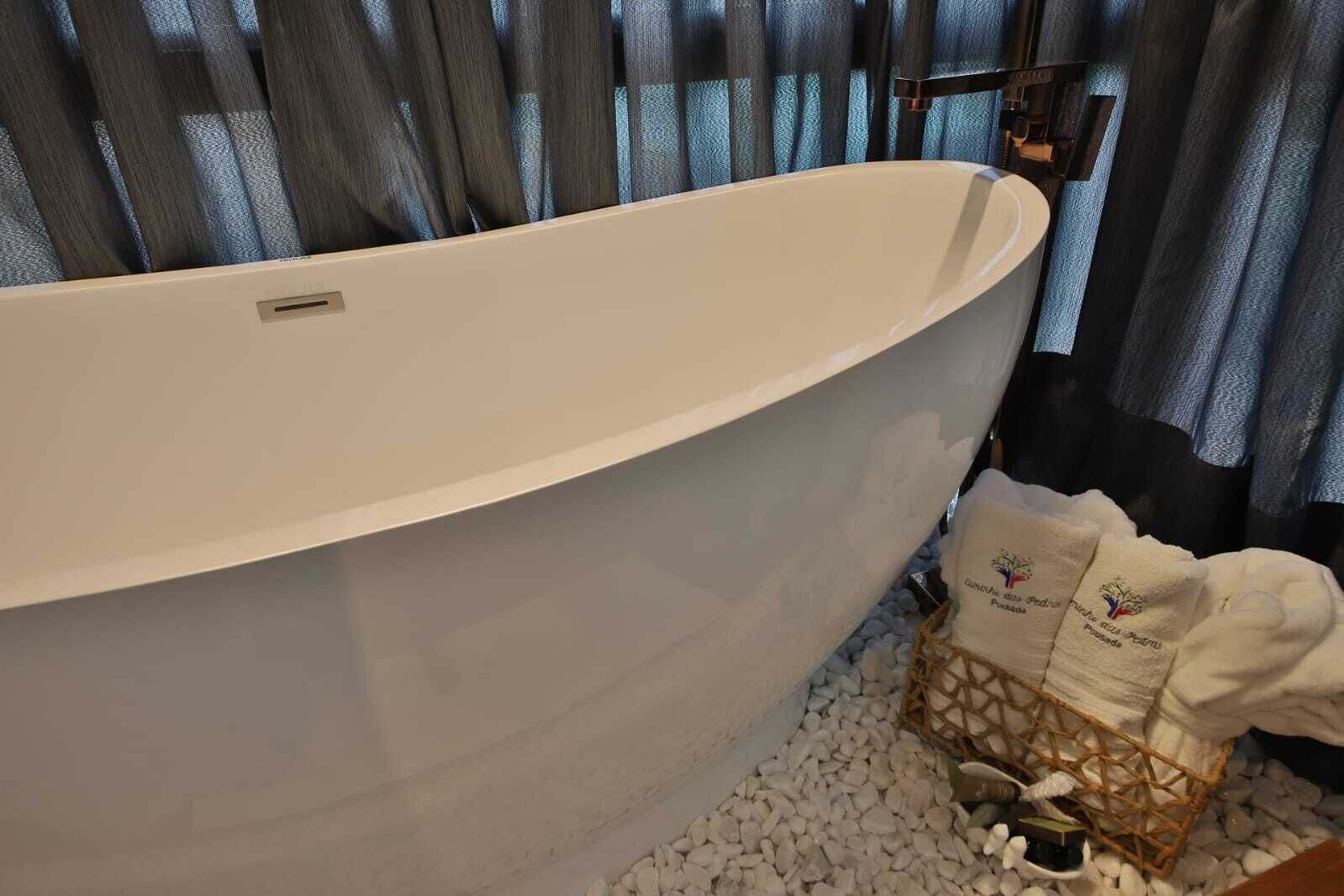 Una bañera independiente grande en un baño, con una cesta de mimbre que contiene toallas y artículos de aseo.