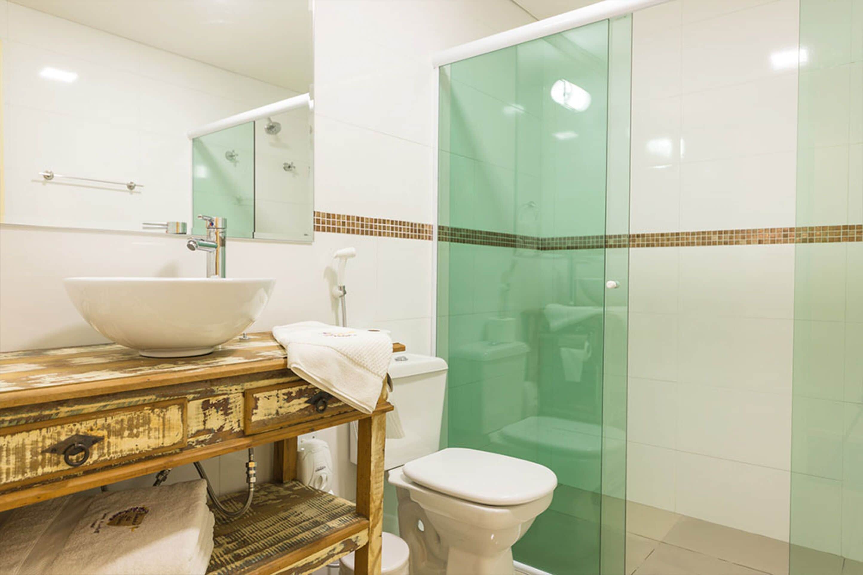 A bathroom with a large white sink, a toilet, and a glass shower enclosure.