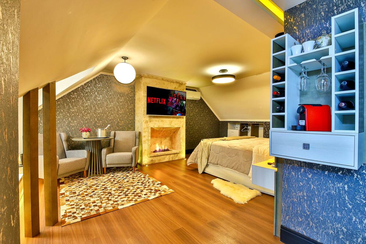 Een moderne slaapkamer met een open haard, een tv aan de muur en een inbouwkast met kristalglas.