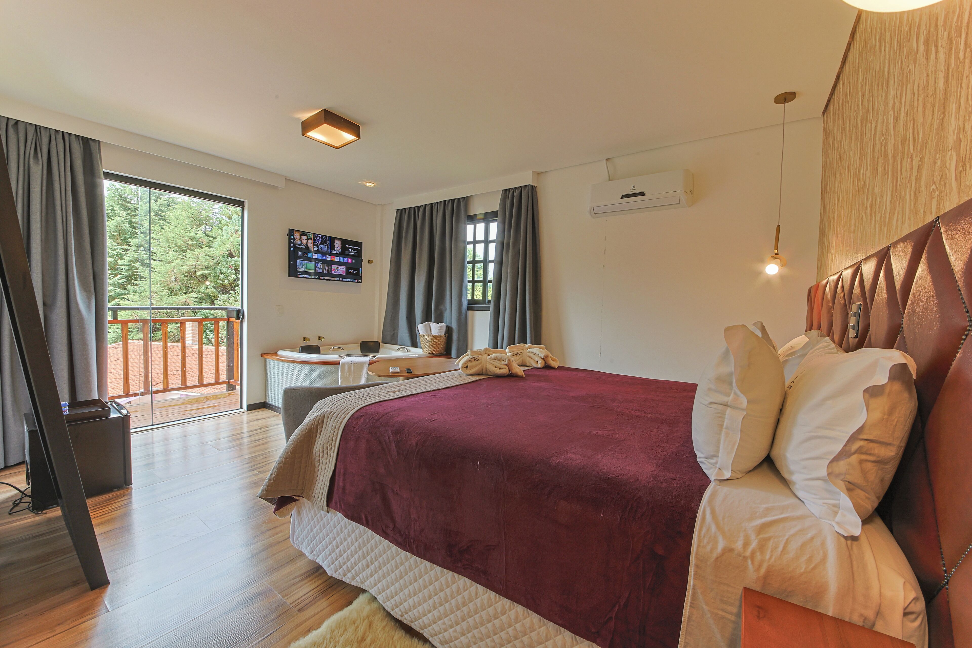 A bedroom with a large bed, a desk, and a balcony.