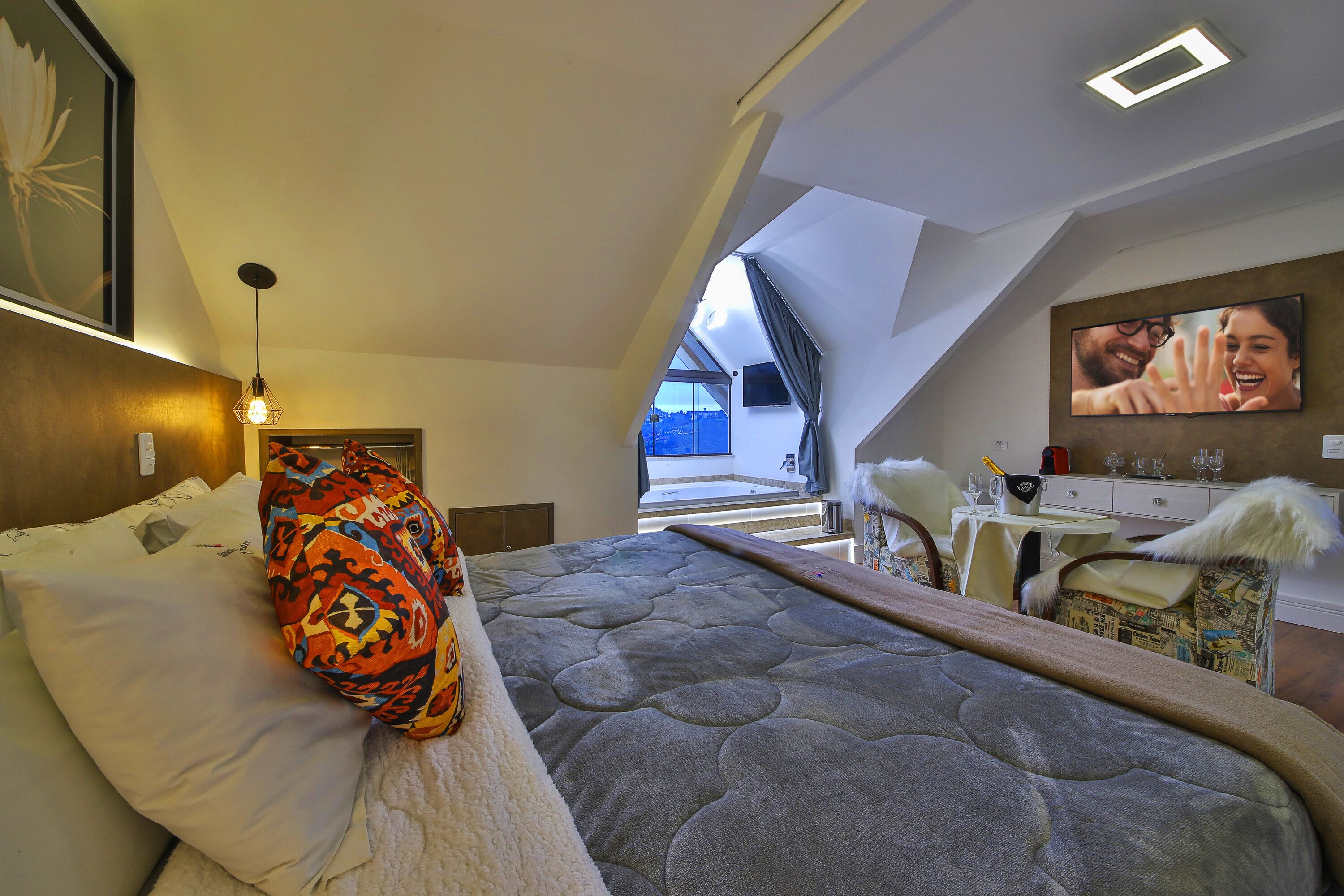 Une chambre à coucher moderne avec un grand lit, une vue sur l’extérieur et un téléviseur fixé au mur.