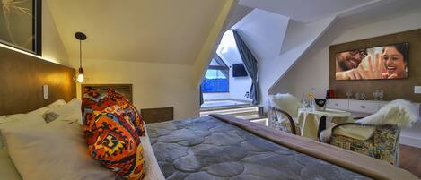 Une chambre à coucher moderne avec un grand lit, une vue sur l’extérieur et un téléviseur fixé au mur.