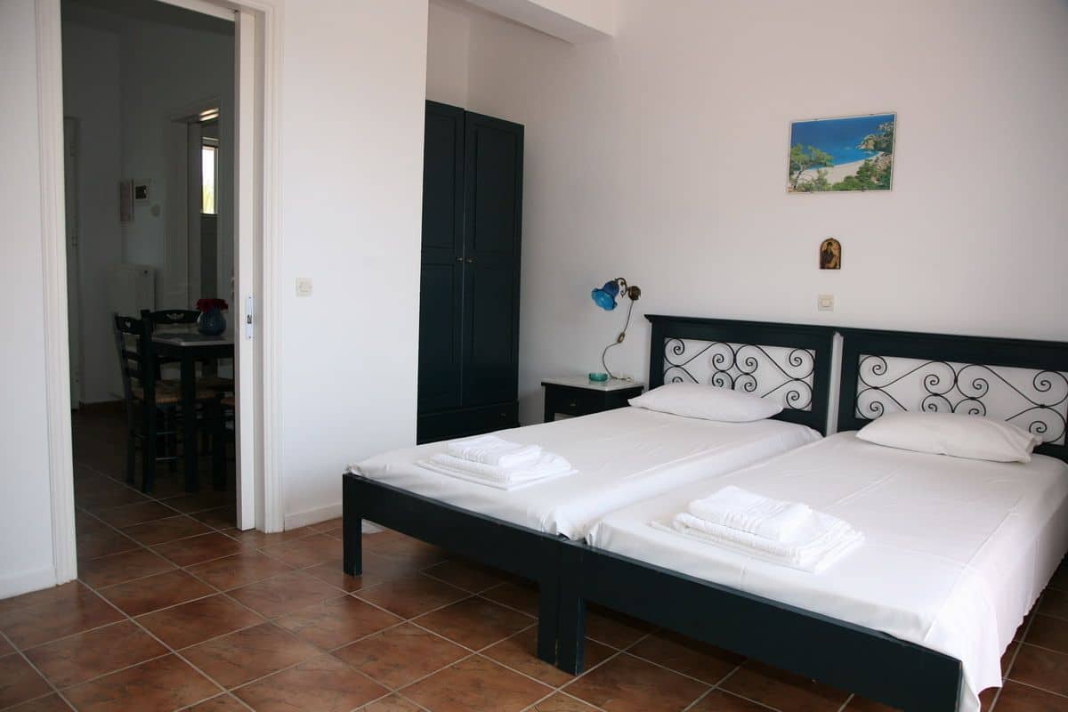 A bedroom with two beds, a dining area, and a view of the sea.
