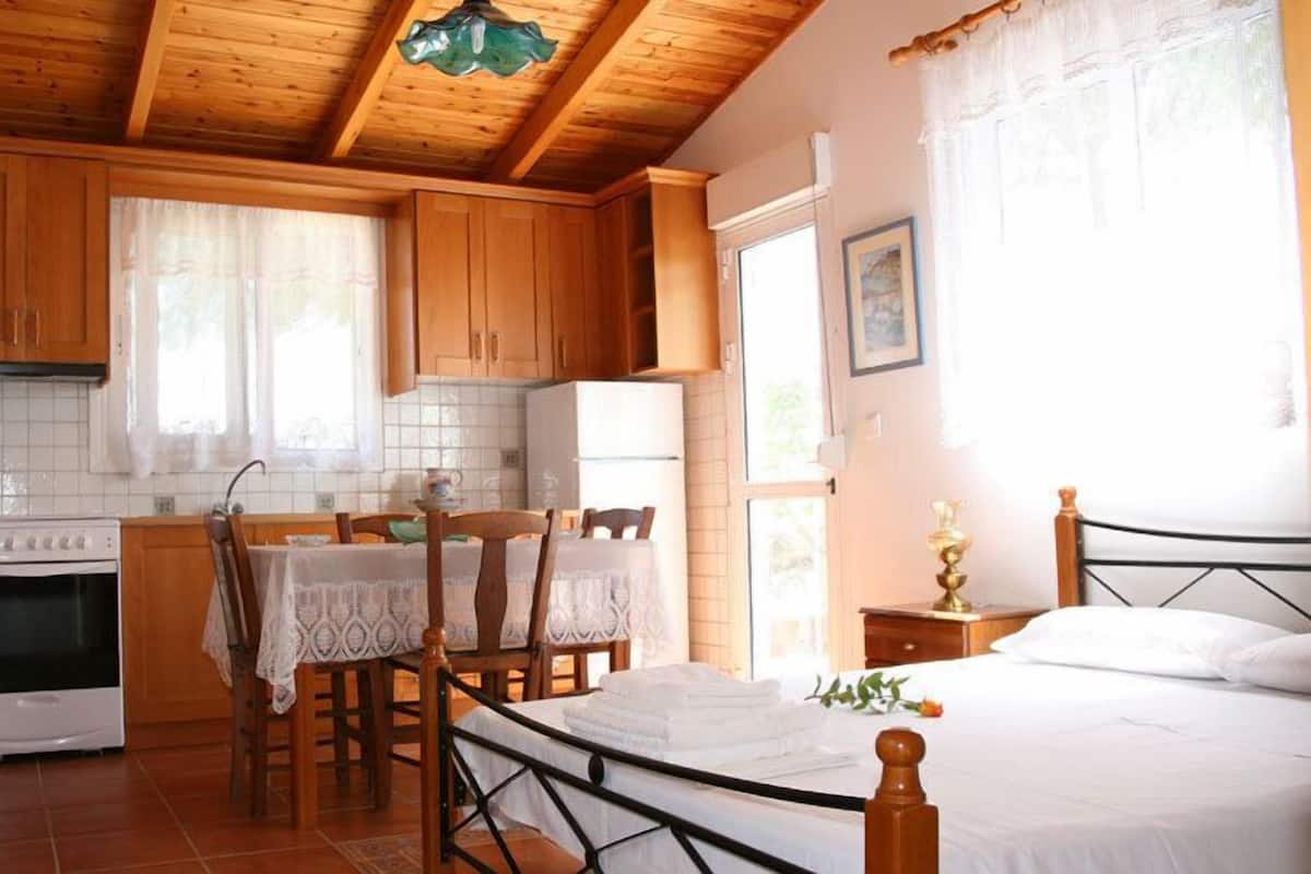 A compact kitchen with wooden cabinets, a stove, and a dining area with a table and chairs.