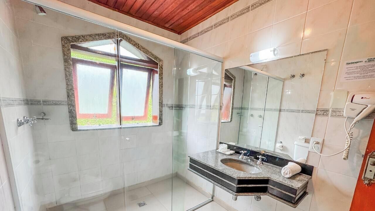 Ein modernes Badezimmer mit Duschabtrennung aus Glas, einem großen Spiegel und einem Waschbecken mit Granitplatte.