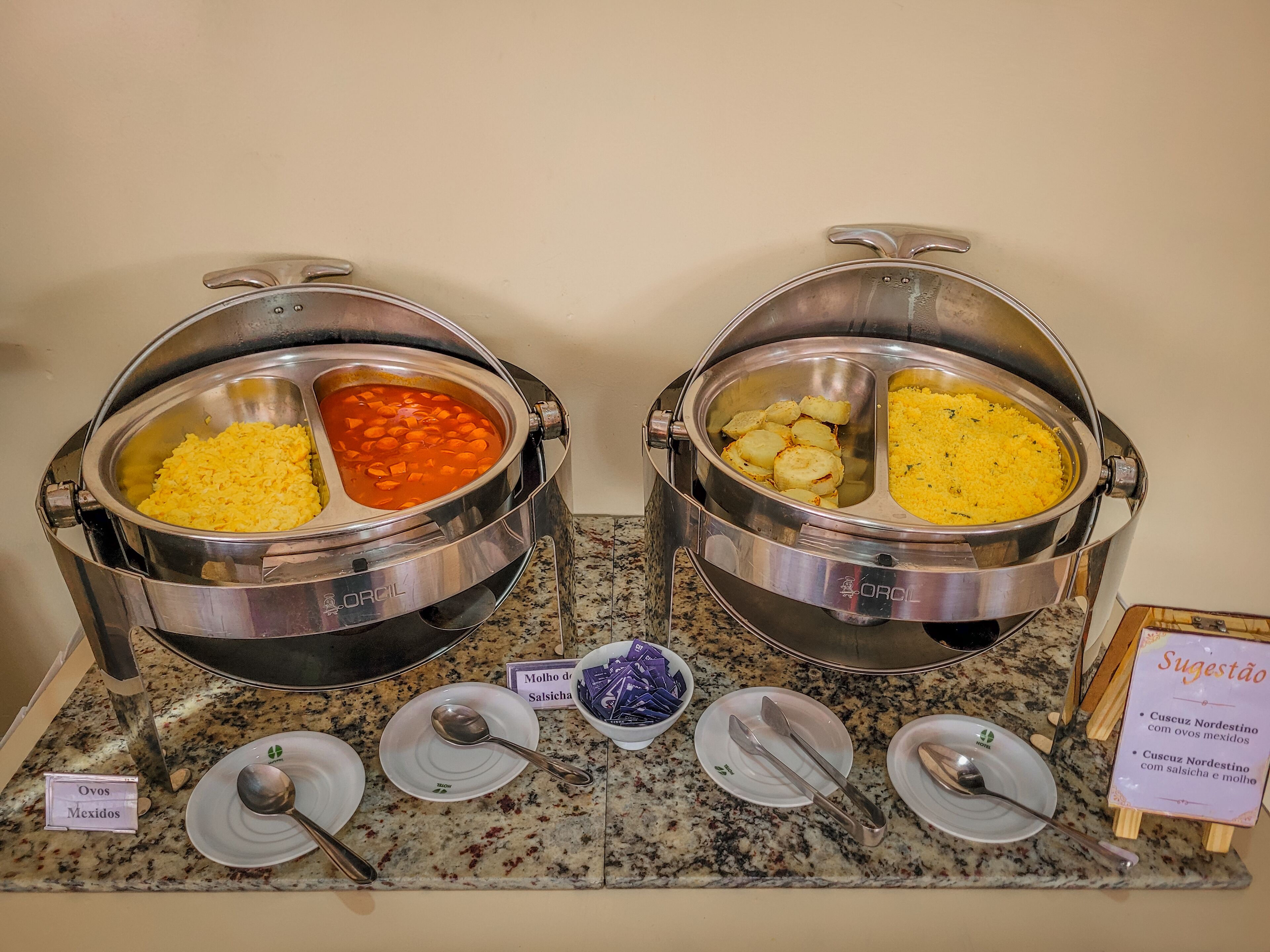 Two buffet stations with labeled dishes including 'Ovos Mexidos' and 'Molho de Salsicha'.