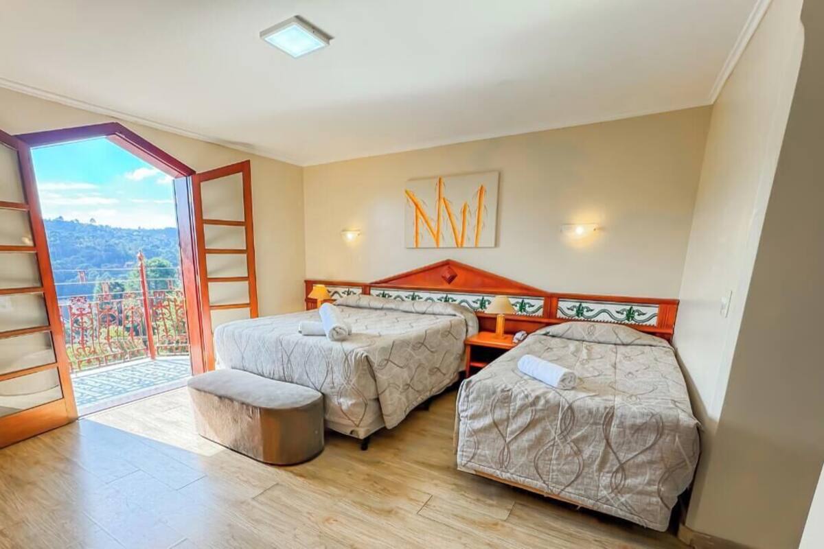 Un dormitorio con dos camas, un balcón y vistas a un paisaje montañoso.