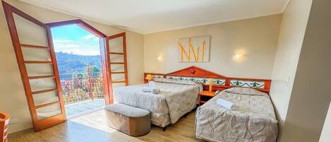 Un dormitorio con dos camas, un balcón y vistas a un paisaje montañoso.