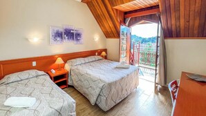 Ein Schlafzimmer mit zwei Betten, einer Holzbalkendecke und einem Balkon mit Blick.