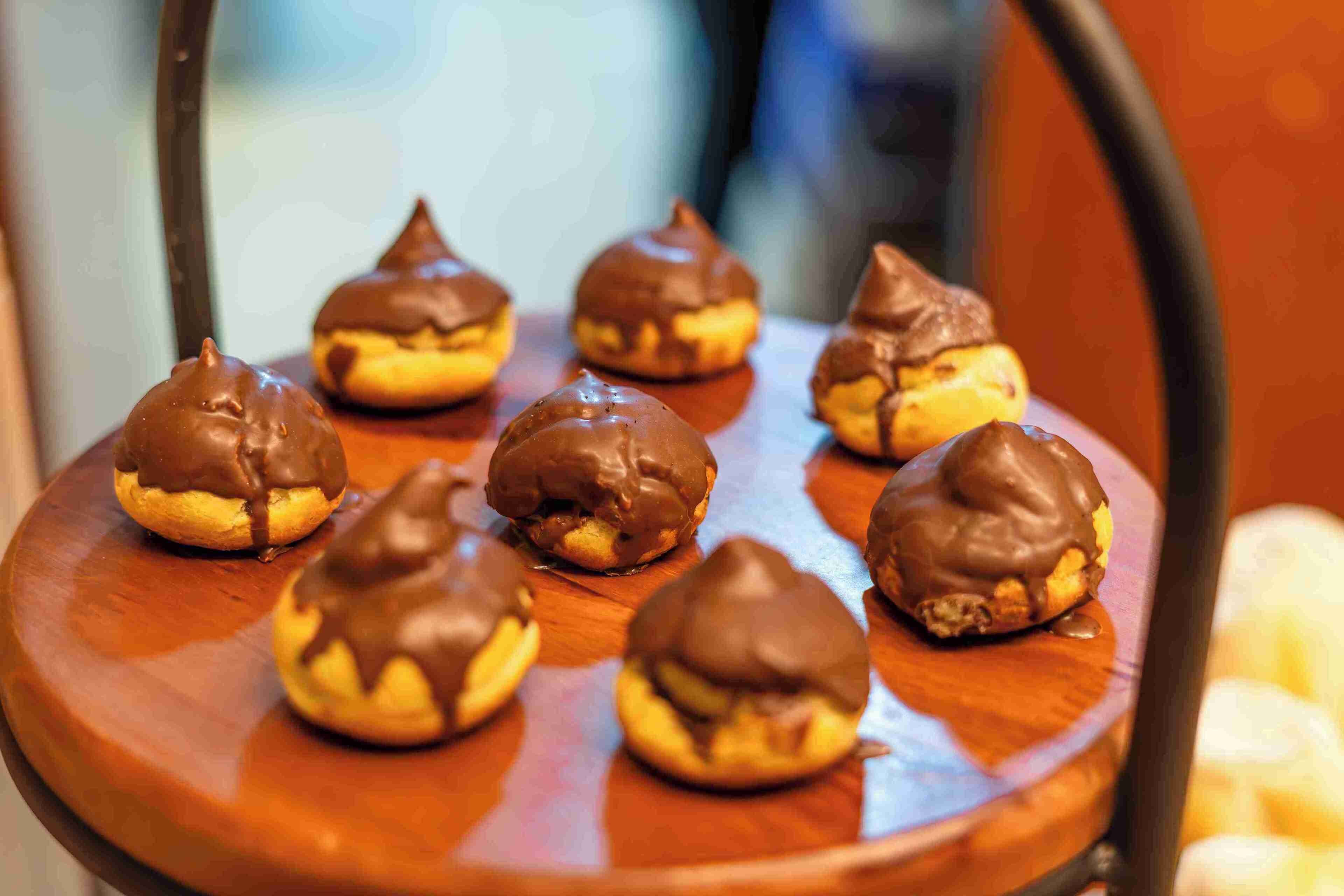 A wooden chair with several chocolate-covered pastries on it.