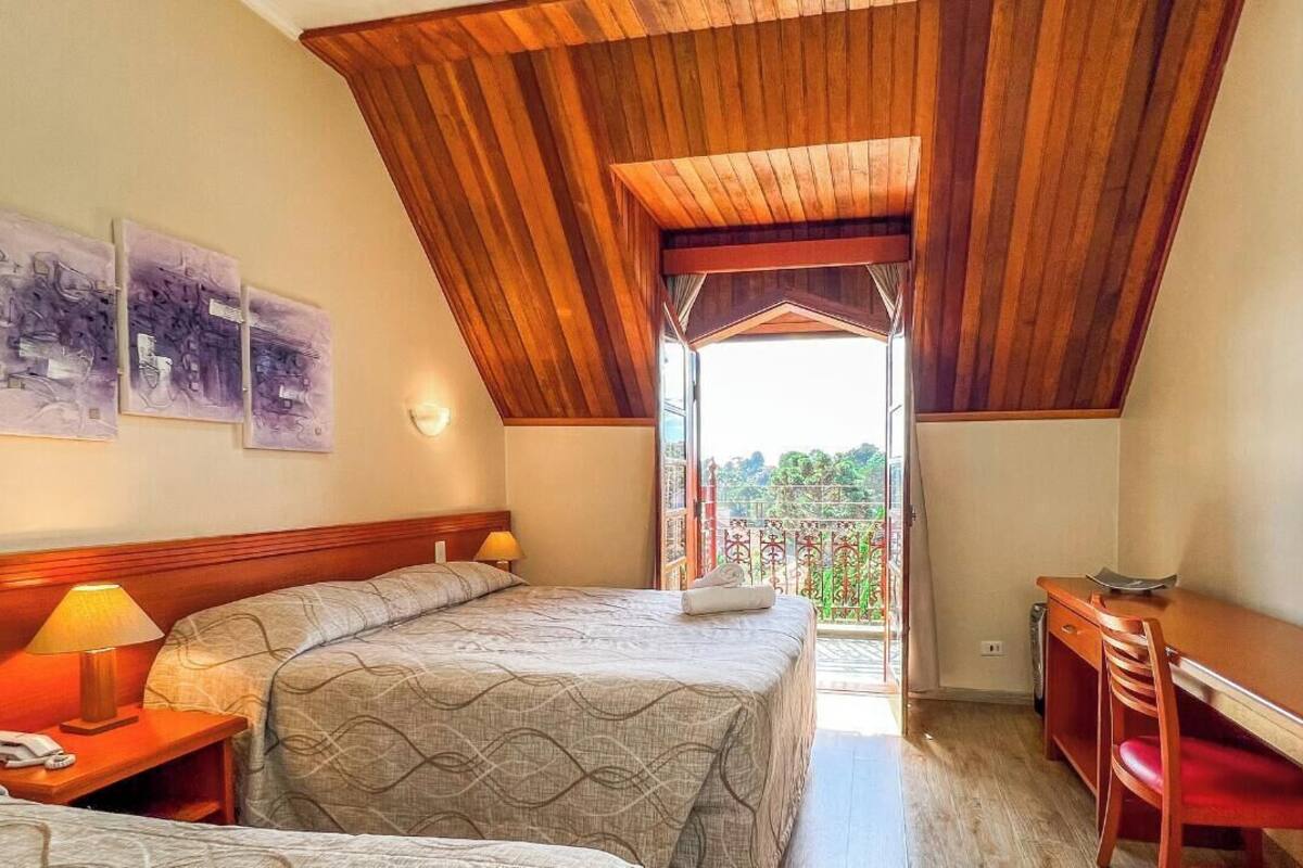 Un dormitorio con dos camas, techo de madera y un escritorio.