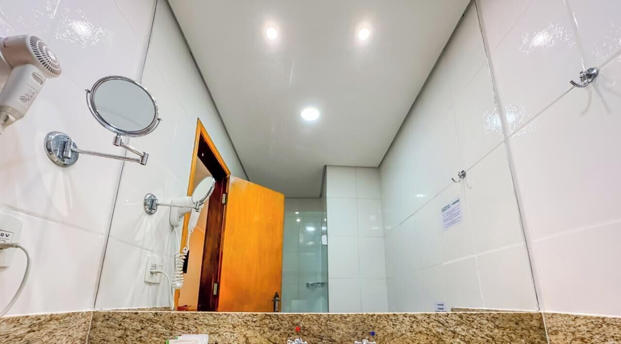 A bathroom with a mirror, hairdryer, and towel rack.