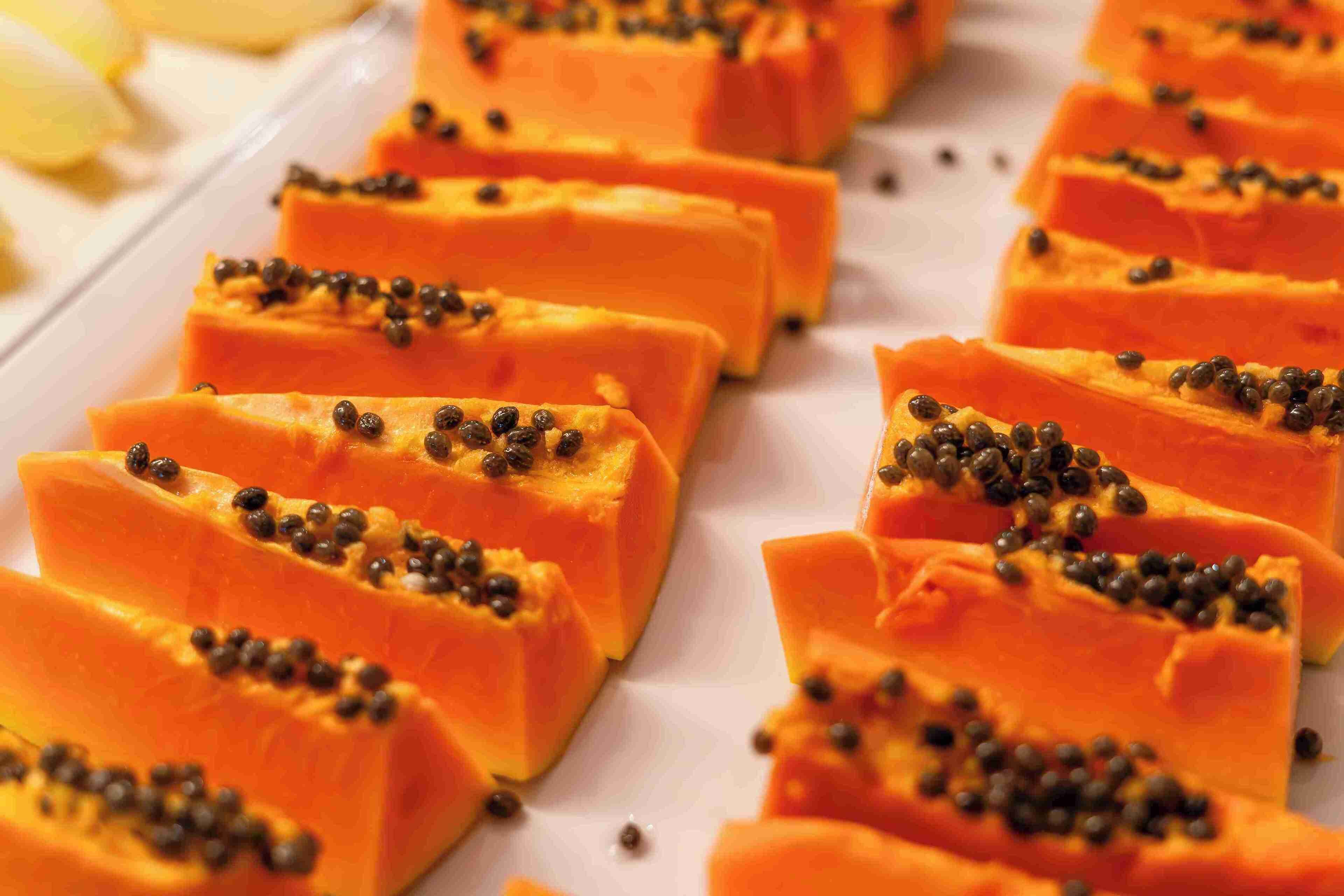 A tray of sliced papaya topped with black seeds.
