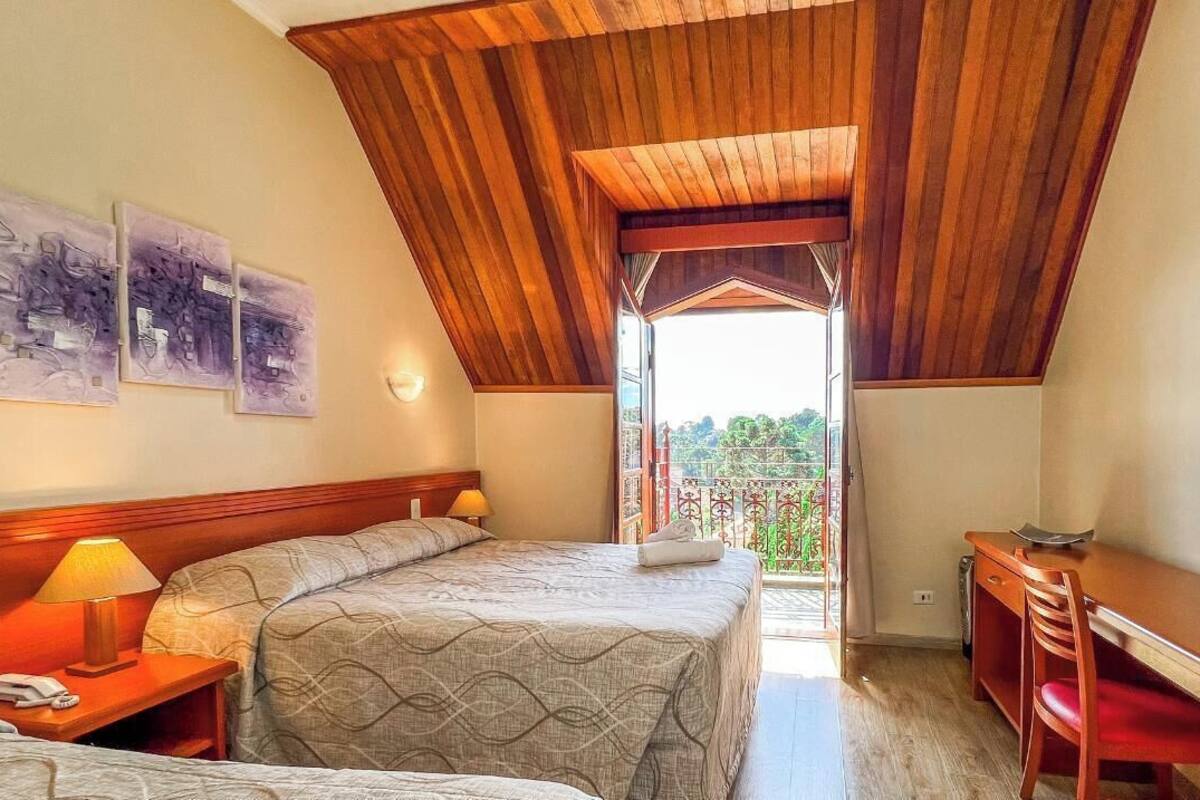 Un dormitorio con dos camas, un escritorio y vistas al exterior.