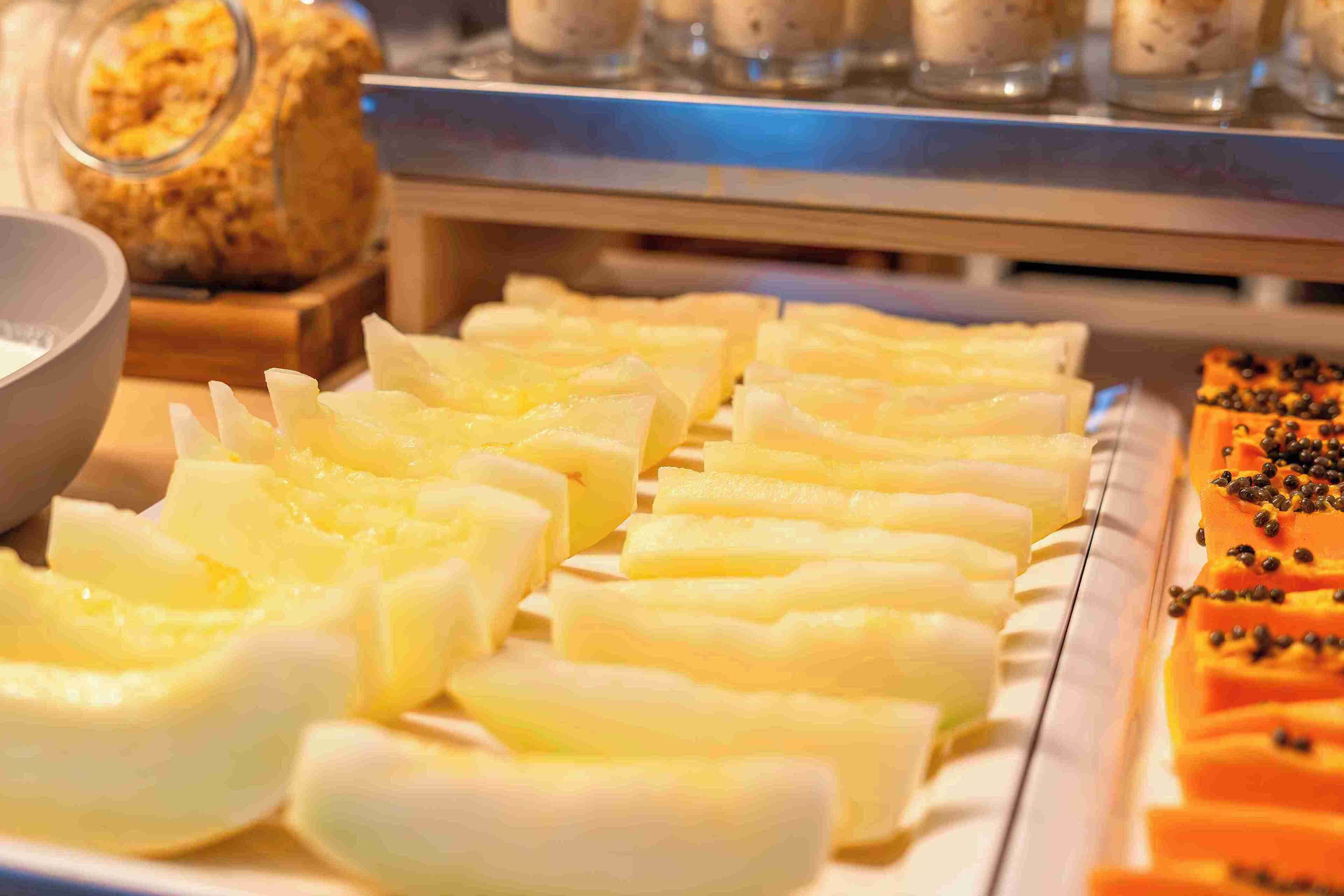 Een buffet met diverse soorten eten, waaronder ananasschijfjes en een gerecht belegd met zwarte peperkorrels.