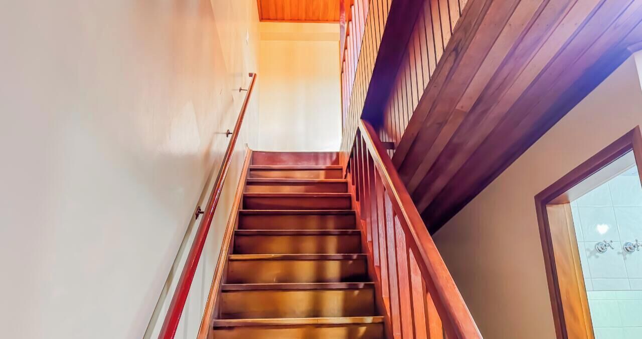 Una escalera de madera con barandilla, que conduce a un piso superior.