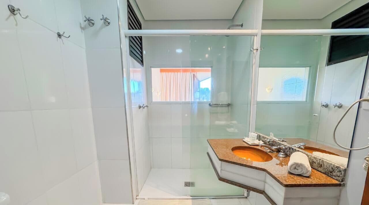 A modern bathroom with a glass-enclosed shower, a marble sink, and a large mirror.